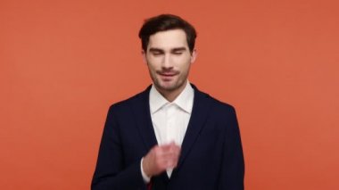Kurnaz bir gülümsemeyle bakan kıskanç bir adamın portresi, aklında hileli bir plan olan, intikam planları yapan, kurnaz ifadelerle avuçlarını ovuşturan. Turuncu arka planda kapalı stüdyo çekimleri