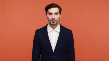 Resmi olarak ciddi sakallı, patronluk taslayan bir ifade takınıyor ve şu anda komutayı verdiğini söylüyor. Turuncu arka planda kapalı stüdyo çekimleri