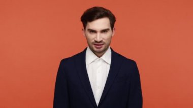 Çılgın esmer adam iş elbisesi giyer. Dişlerini sıkar ve yumruklarını nefret içinde kaldırır. Öfkeden hırıldar. Turuncu arka planda kapalı stüdyo çekimleri