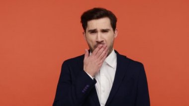 Uyku vakti. Uykulu, sakallı, siyah takım elbiseli, yorgun, avuç içlerini birbirine yakın tutan, uykuya dalan bir ofis çalışanı. Turuncu arka planda kapalı stüdyo çekimleri