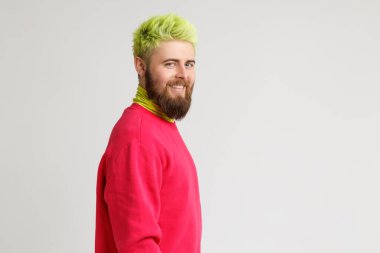 Neşeli sakallı beyaz adamın profili neşeli bir ifadeye sahip geniş gülümsüyor, beyaz mükemmel dişleri var, kırmızı kazak giyiyor, kameraya bakıyor. Uzayı kopyala Gri arka planda izole edilmiş kapalı stüdyo görüntüleri.