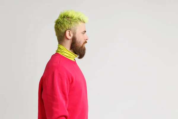 髭と黄色の髪を持つ男のサイドビューの肖像画は 先に彼の真剣で自信を持って表現で 赤いジャンパーを着て コピースペースを探している 灰色の背景に隔離された屋内スタジオショット — ストック写真