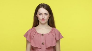 Sevmemek, kötü hizmet! Pembe elbiseli, hoşnutsuz esmer kadın baş parmağını kaldırıyor ve hoşnutsuzca surat asıyor, olumsuz geri bildirim yapıyor. Sarı arka planda kapalı stüdyo çekimleri.