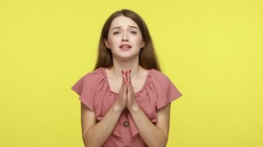 Lütfen, yalvarıyorum! Kahverengi saçlı, zarif elbiseli, kameraya hitap eden, yalvaran gözlerle dua eden çekici bir genç kadın. Sarı arka planda kapalı stüdyo çekimleri.