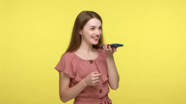Mobil akıllı dijital teknoloji. Güzel genç bir kadın akıllı telefonla konuşuyor, sanal asistanla internette bilgi arıyor, mesaj kaydediyor. Sarı arka planda kapalı stüdyo çekimleri.