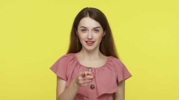 カメラを指差すピンクの指で茶色の髪を持つ素敵な喜びの少女は 幸せな顔の表情 笑顔と示すと探しています 黄色の背景に隔離された屋内スタジオショット — ストック動画