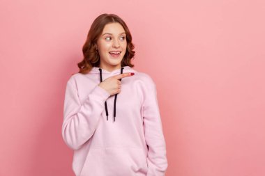 Yüzünde dişlek bir gülümseme ve reklamınız için boş bir boşluk olan neşeli genç bir kadının portresi. Pembe arka planda kapalı stüdyo çekimleri