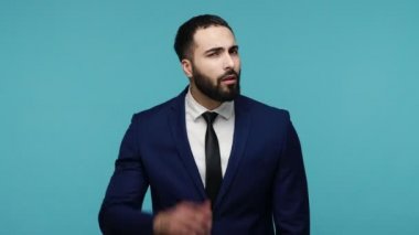 Sağırlık ve işitme sorunları. Dikkatli esmer, takım elbiseli, sakallı bir adam kulağının yanında durup dikkatlice konuşmaları dinliyor. Gizli haberler. Mavi arka planda kapalı stüdyo çekimi.