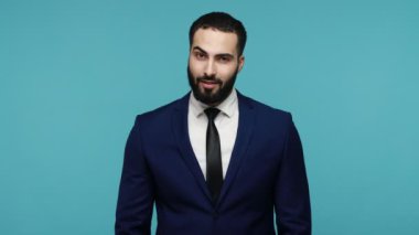 Resmi stil kıyafetli, kurnaz bir gülümseme takınıp kurnaz bir planı olan ya da intikam planı yapan zeki bir adamın şeytani bir ifadesi vardır. Mavi arka planda kapalı stüdyo çekimi.