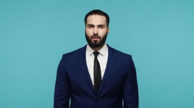 Çık dışarı! Sakallı yakışıklı işadamı kavga ederken tekmeliyor, onu rahat bırakmasını istiyor, kızgın bir şekilde kameraya bakıyor. Mavi arka planda kapalı stüdyo çekimi.