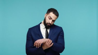 Yaralı el. Sakallı, sakallı, sakallı, bileği ağrılı, eli burkulmuş, eklem iltihabı, karpal tünel sendromu var. Mavi arka planda kapalı stüdyo çekimi.