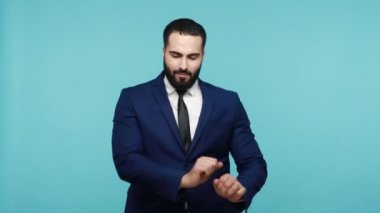 Resmi tarzda giyinmiş neşeli sakallı adam müzik eşliğinde dans edip şarkı söyleyerek eğleniyor, dinleniyor ve eğleniyor. Mavi arka planda kapalı stüdyo çekimi.