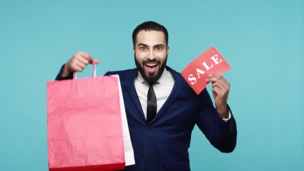 Vreugdevolle Opgewonden Man Met Baard Business Suit Houdt Boodschappentassen Verkoopwoord — Stockvideo