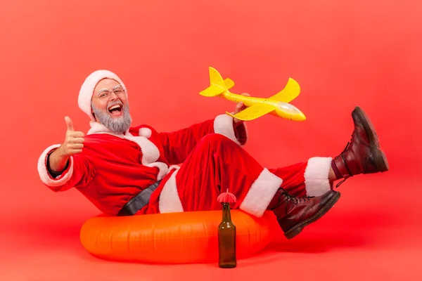 Szczęśliwy Staruszek Kostiumie Świętego Mikołaja Siedzący Pomarańczowym Gumowym Pierścieniu Trzymający — Zdjęcie stockowe
