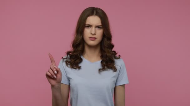 気をつけて 青いTシャツのスケーリングで深刻な波状の髪の女性は 指でジェスチャーを作る警告し 注意を払って 注意してください 屋内スタジオはピンクの背景に隔離されたショット — ストック動画