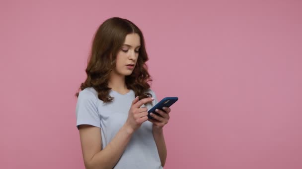 Σοκαρισμένη Νεαρή Γυναίκα Κυματιστά Μαλλιά Shirt Χρησιμοποιώντας Κινητό Τηλέφωνο Πληκτρολογώντας — Αρχείο Βίντεο