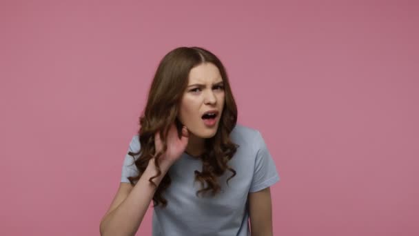 머리에 티셔츠를 소녀가 귓가에 대화를 스튜디오 가핑크 배경으로 — 비디오