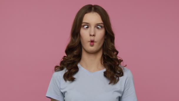 Humorvolles lustiges hübsches Teenie-Mädchen in lässigem T-Shirt, das Fischgesicht mit schmollenden Lippen macht und komische dumme Fratzen, kindliches Verhalten zeigt. Indoor-Studio isoliert über rosa Hintergrund aufgenommen.