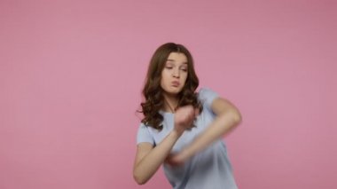 Tişörtlü mutlu genç kız başarıyı dans figürleriyle kutluyor, ünlü internet zafer mim 'i, dokunaklı trendler sergiliyor. Pembe arka planda kapalı stüdyo çekimleri.