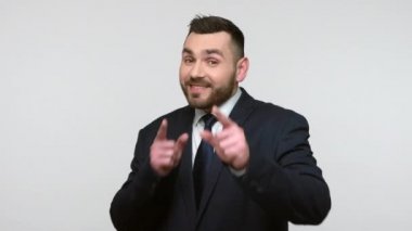 Siyah resmi takım elbiseli, gülümseyen sakallı iş adamının portresi seni kazanan olarak göstererek mutluluğu ifade ediyor. Gri arka planda izole edilmiş kapalı stüdyo görüntüleri.