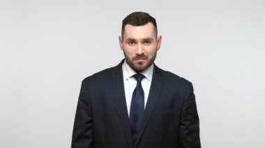 Siyah takım elbiseli sakallı işadamı el kol hareketleri yapıyor, yeter, sorunları reddediyor, çatışmayı reddediyor. Gri arka planda izole edilmiş kapalı stüdyo görüntüleri.