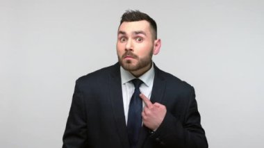 Vay canına, bu benim! Siyah resmi takım elbiseli, şaşkın sakallı iş adamı şaşırmış bir ifadeyle, kendi başarısıyla gurur duyuyor. Gri arka planda izole edilmiş kapalı stüdyo görüntüleri.