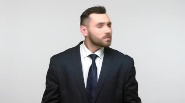 Siyah takım elbiseli sakallı iş adamı kulaklarını tıkayan gürültüden bıkmış, rahatsız edici sesleri, rahatsız edici sesleri durdurmak istiyor. Gri arka planda izole edilmiş kapalı stüdyo görüntüleri.