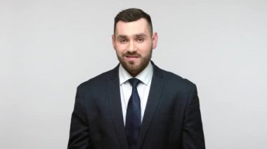 Kendine güvenen, kendine güvenen, takım elbiseli, kaslarını gösteren, gücünden gurur duyan, başarıya ulaşmak için büyük bir güç hisseden kendini beğenmiş, kibirli bir iş adamı. Gri arka planda izole edilmiş kapalı stüdyo görüntüleri.