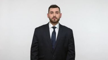 Siyah resmi takım elbiseli sakallı işadamı mutluluktan bağırarak yukarı bakıyor yukarıdan yağan para yağmurunun altında duruyor, zenginliğin tadını çıkarıyor. Gri arka planda izole edilmiş kapalı stüdyo görüntüleri.