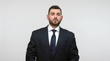 Siyah resmi takım elbiseli, gururlu, gururlu iş adamı altın taç takıyor, kendini beğenmiş egoizm kavramı, kameraya bakıyor. Gri arka planda izole edilmiş kapalı stüdyo görüntüleri.