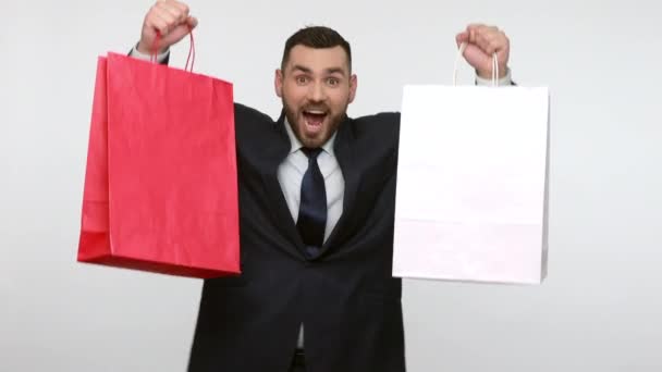 쇼핑백을 성공적 구매를 축하하는 사업가 은회색 배경에 고립되어 있었다 — 비디오