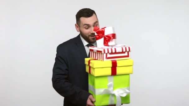 身穿黑色官服的大胡子商人高兴地收到礼物 拥抱着一堆堆礼品盒 看上去很高兴 在灰色背景下被隔离的室内拍摄 — 图库视频影像