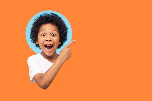 광고하네 머리가 곱슬곱슬 광고용 복제품 자리를 가리키는 아이의 실내는 주황색 — 스톡 사진
