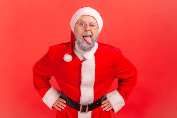 Nieposłuszny Zabawny Staruszek Szarą Brodą Kostiumie Świętego Mikołaja Demonstrujący Język — Zdjęcie stockowe