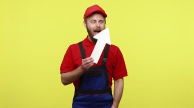 Son derece mutlu işçiler beyaz kağıt oklarını gösteriyor, sipariş ve maaş artışlarını gösteriyor, mavi üniforma, kırmızı tişört ve güneşlik şapkası giyiyor. Sarı arka planda izole edilmiş kapalı stüdyo çekimi