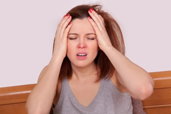 Gripe ou frio. Close-up vista superior imagem de uma jovem frustrada com nariz vermelho e sofrendo de terrível dor de cabeça na cama — Fotografia de Stock