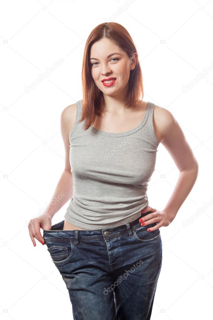 全长画像的苗条欧洲年轻漂亮微笑的女人在大牛仔裤显示成功减肥与她快乐的脸 白色的背景上孤立 图库照片 C Khosrork