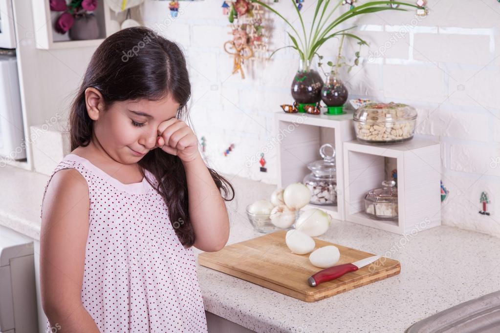 Beautiful small middle eastern girl crying in kitchen, tears of onion.