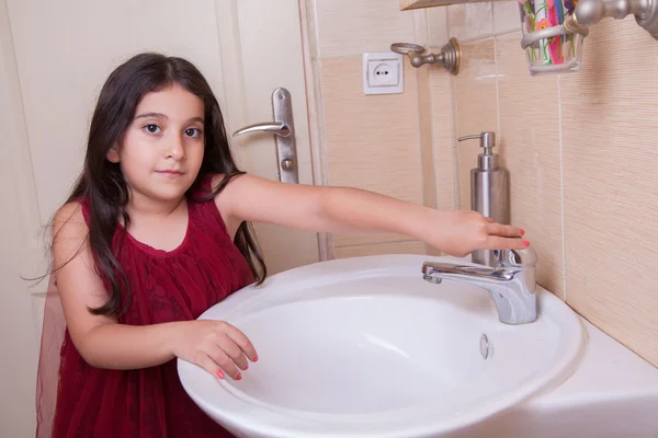 One beautiful little middle eastern arab girl with red dress is washing her hands — Stock Photo, Image