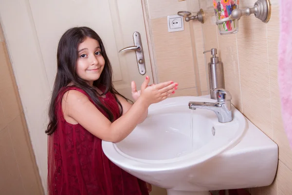 One beautiful little middle eastern arab girl with red dress is washing her hands — Stock Photo, Image