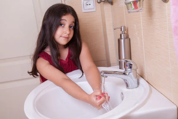 Uma bela menina árabe médio oriental com vestido vermelho está lavando as mãos — Fotografia de Stock
