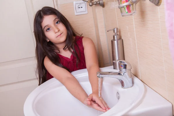 One beautiful little middle eastern arab girl with red dress is washing her hands — Stock Photo, Image