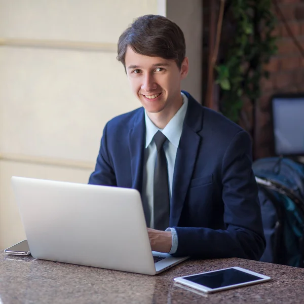 One relaxed young handsome professional businessman working with his laptop, phone and tablet in a noisy cafe. — Stock Photo, Image