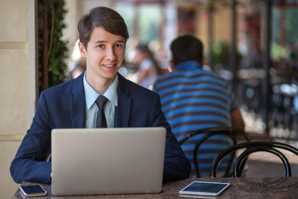 One relaxed young handsome professional businessman working with his laptop, phone and tablet in a noisy cafe. — Stock Photo, Image