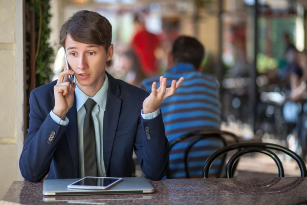 One relaxed young handsome professional businessman working with his laptop, phone and tablet in a noisy cafe. — Stock Photo, Image