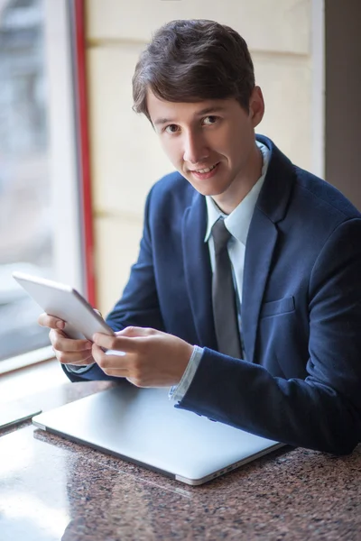 One relaxed young handsome professional businessman working with his laptop, phone and tablet in a noisy cafe. — Stock Photo, Image