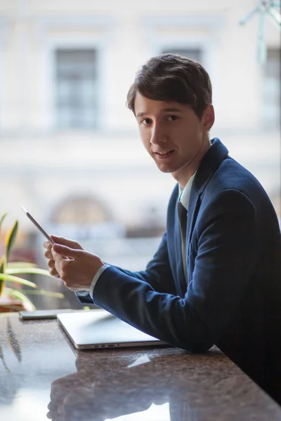 One relaxed young handsome professional businessman working with his laptop, phone and tablet in a noisy cafe. — Stock Photo, Image