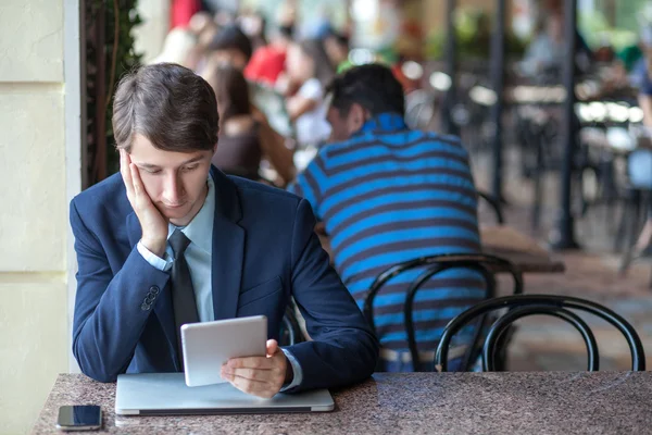 One relaxed young handsome professional businessman working with his laptop, phone and tablet in a noisy cafe. — Stock Photo, Image