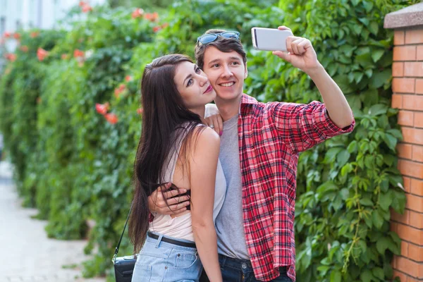 Feliz joven pareja haciendo selfie por teléfono móvil inteligente en la ciudad . — Foto de Stock