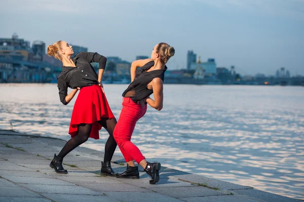 Дві молоді красиві сестри-близнюки танцюють танцюючий танець на міському фоні біля річки . — стокове фото